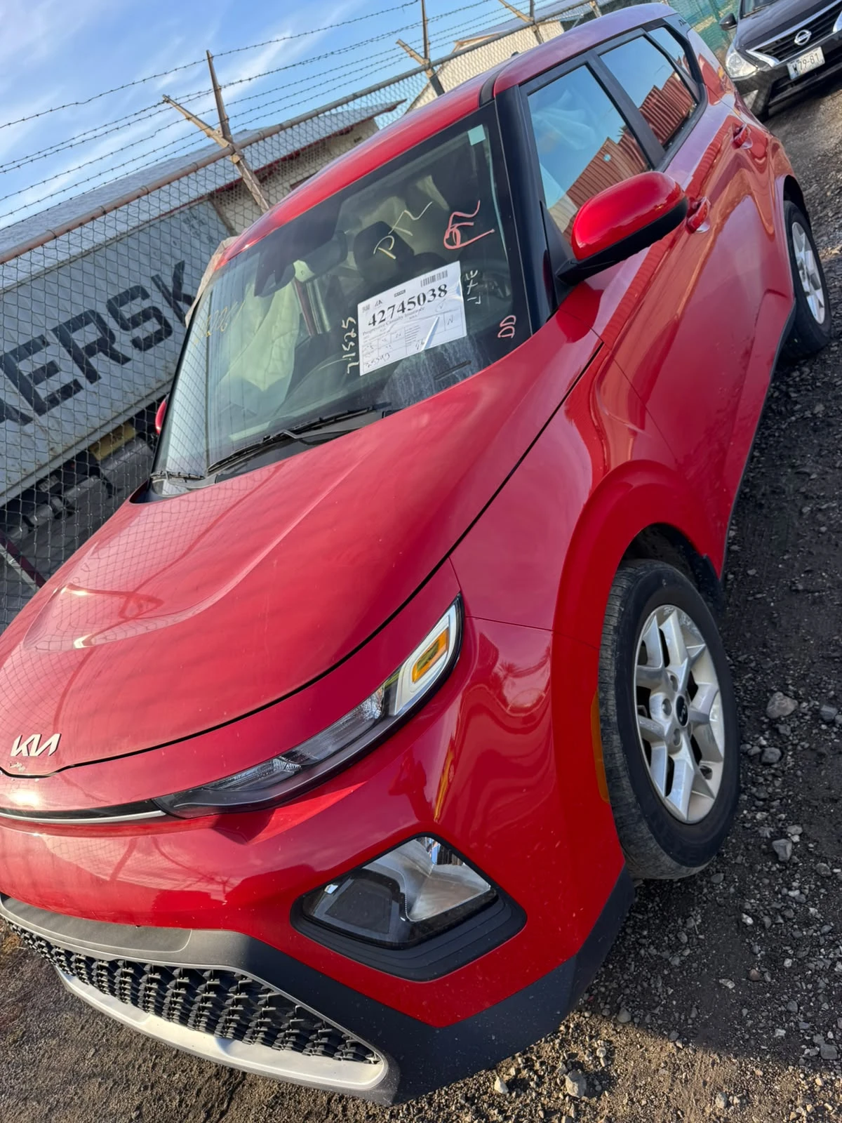 Red Kia Soul bought at auction, in a shipping yard